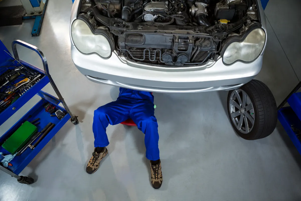 Overhead view of a mechanic working under a raised car